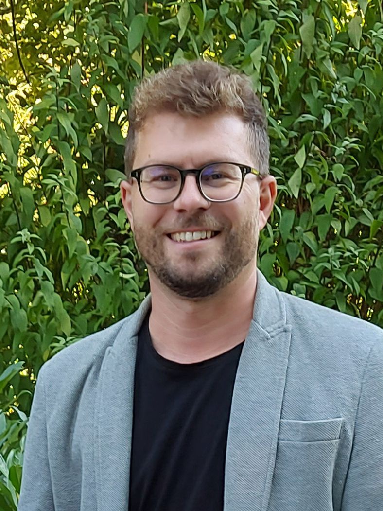 Mann mit Brille und kurzen Haaren blickt in die Kamera.